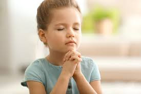 young girl praying with eyes closed