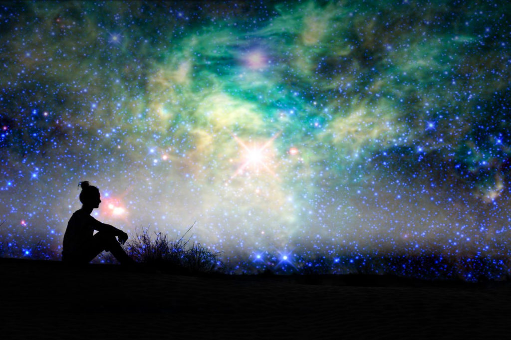 silhouette woman sitting in field against vibrant night sky