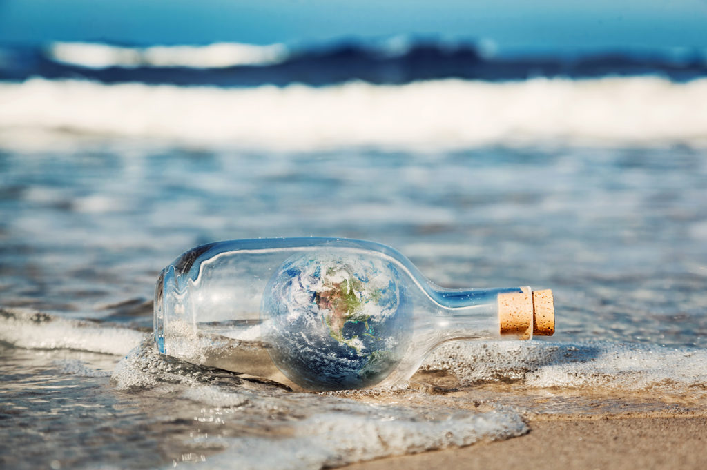 Earth in the bottle coming with wave from ocean. Environment, clean world message